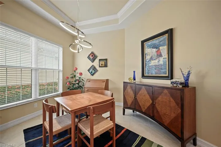 Dining space with crown molding, light tile patterned flooring, and a tray ceiling