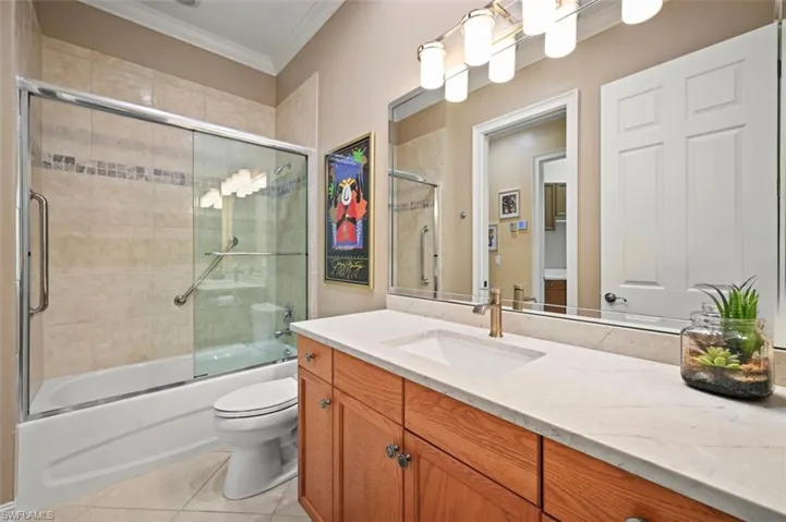 Full bath featuring crown molding, tile patterned floors, vanity, and combined bath / shower with glass door