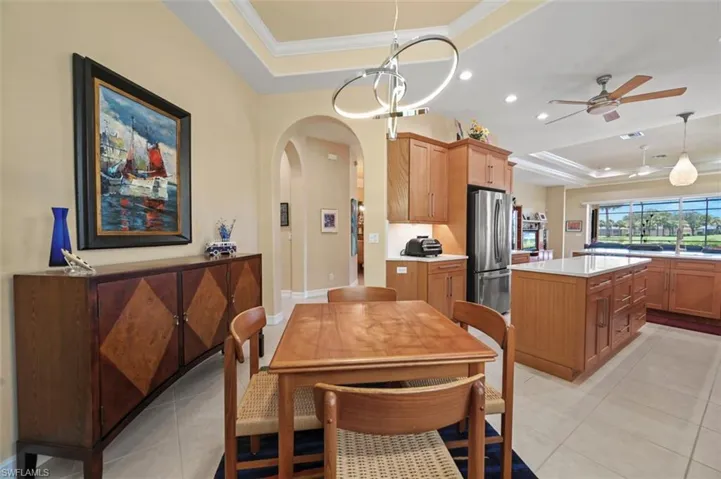 Dining space with a tray ceiling, arched walkways, recessed lighting, ceiling fan, and ornamental molding