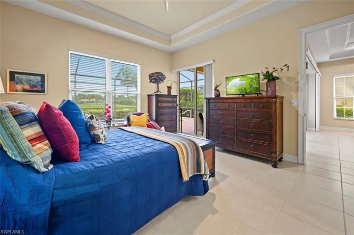 Bedroom with a tray ceiling, light tile patterned floors, crown molding, and access to outside