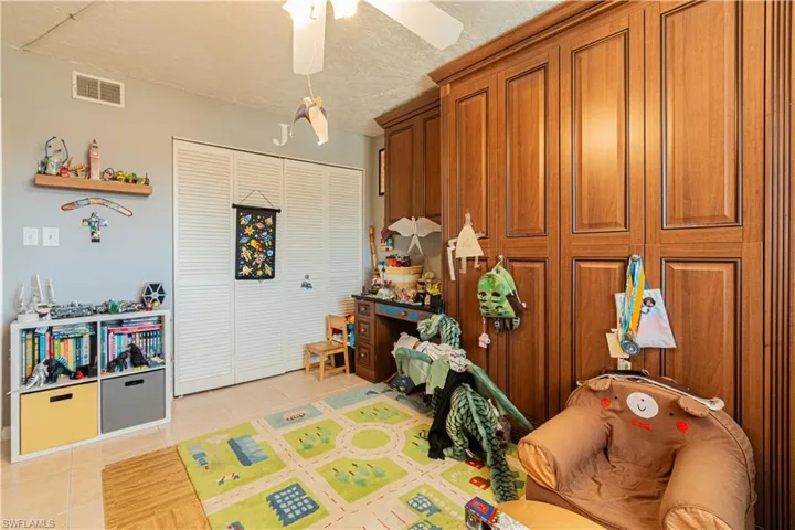 Recreation room with ceiling fan, light tile patterned flooring, and a textured ceiling