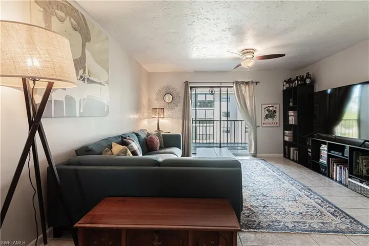 Living room with light tile patterned floors, a textured ceiling, and ceiling fan