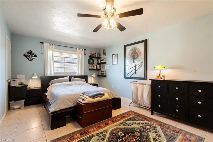 Bedroom with light tile patterned floors, a textured ceiling, and ceiling fan