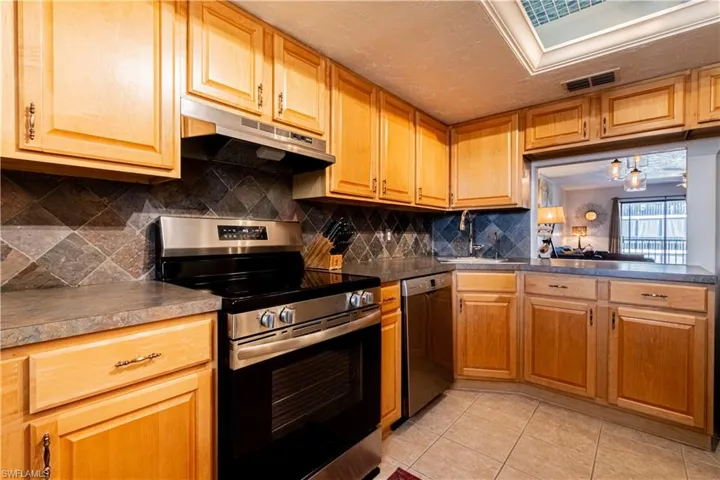 Kitchen featuring decorative backsplash, sink, light tile patterned flooring, and appliances with stainless steel finishes