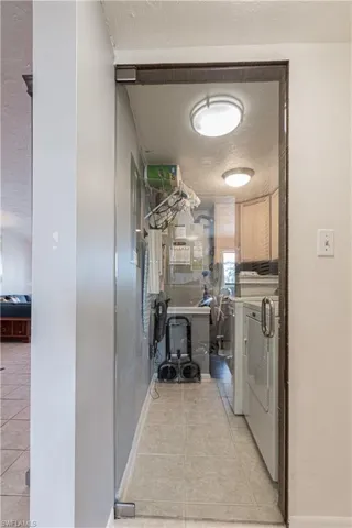 Washroom featuring cabinets, light tile patterned floors, a textured ceiling, and separate washer and dryer