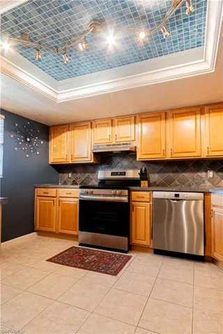 Kitchen with a raised ceiling, light tile patterned floors, and stainless steel appliances