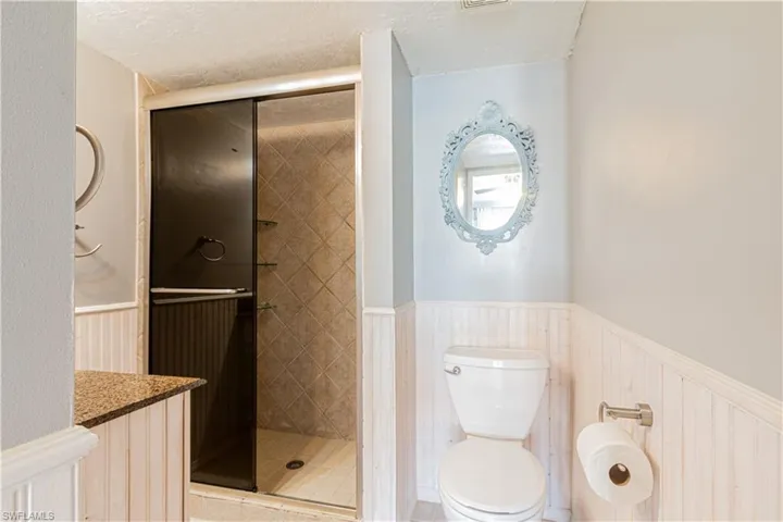 Bathroom featuring an enclosed shower, vanity, toilet, and a textured ceiling