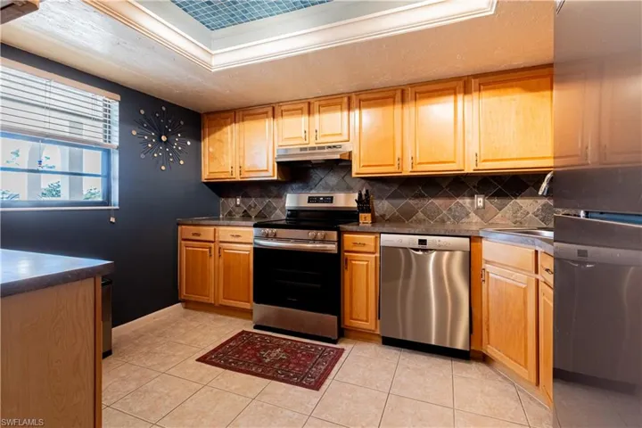 Kitchen featuring sink, appliances with stainless steel finishes, backsplash, and light tile patterned flooring