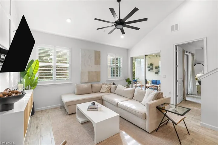 Bright living area featuring vaulted ceilings, recessed lighting, and a modern ceiling fan