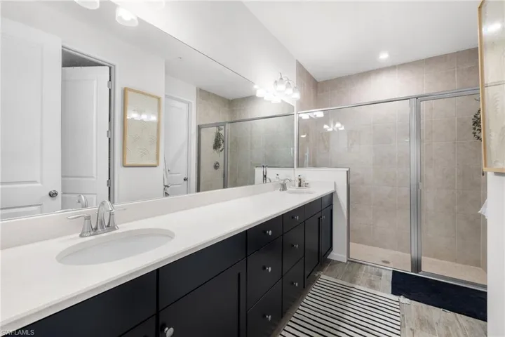 Bathroom featuring a dual vanity with white countertops, dark cabinetry, and brushed nickel fixtures
