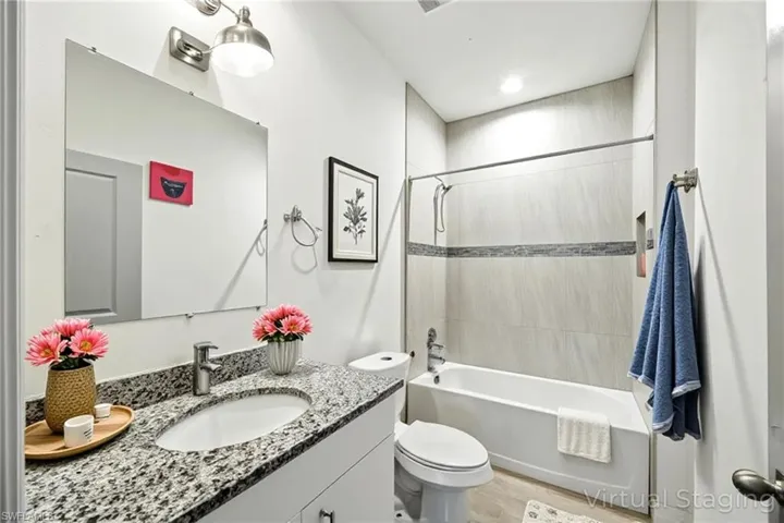 Bathroom with vanity, shower / bathtub combination, and light wood-style floors