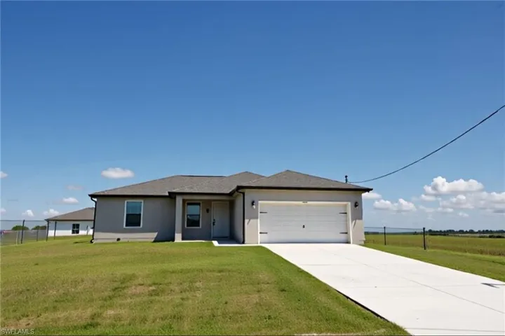 View of front of home with stucco siding, concrete driveway, and an attached garage