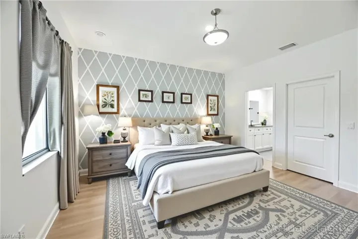 Bedroom featuring an accent wall, light wood-type flooring, and ensuite bathroom