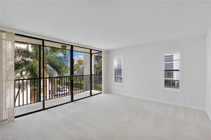 Carpeted spare room featuring baseboards and expansive windows