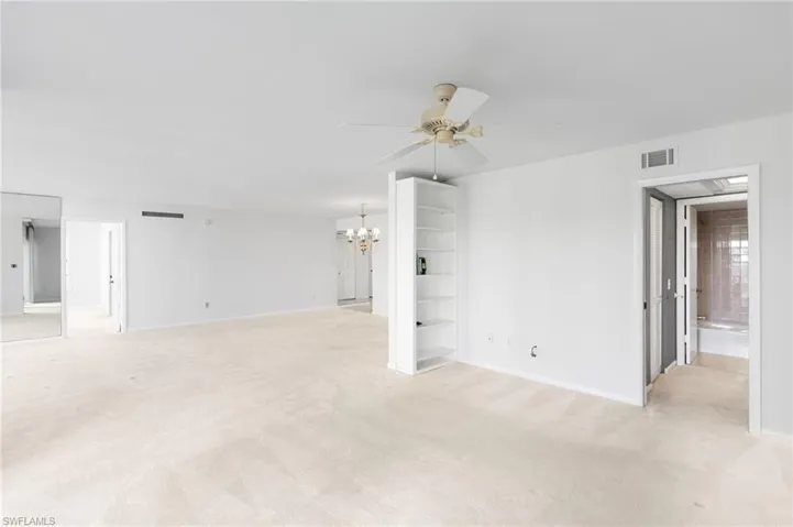 Unfurnished room with light carpet, a chandelier, and a ceiling fan