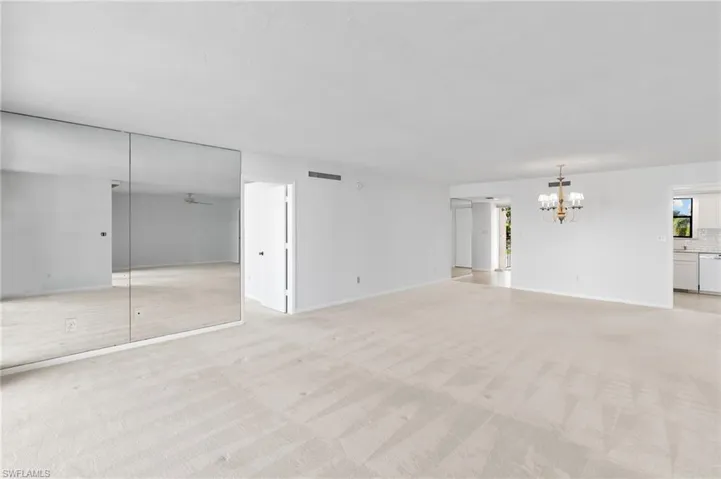 Unfurnished living room featuring light carpet and a chandelier