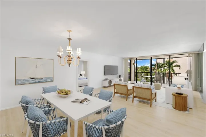 Dining area featuring light wood-style floors, a wall of windows, and a chandelier