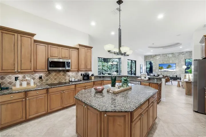 Kitchen featuring wood finish cabinets, dark stone counters, a center island, and stainless steel appliances