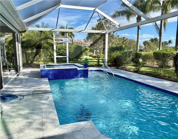 View of pool with glass enclosure, a patio area, and an in ground hot tub