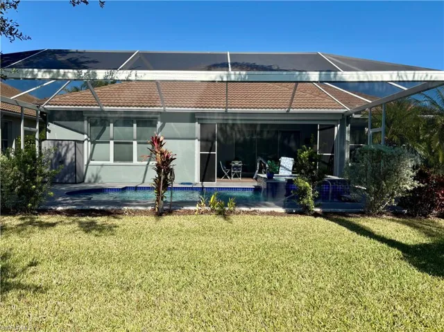 Back of house featuring a lawn and glass enclosure