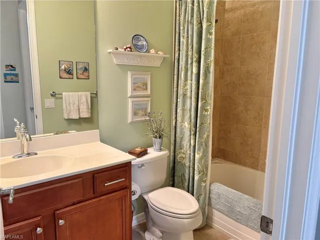 Full bathroom with vanity, shower / bath combination with curtain, and toilet