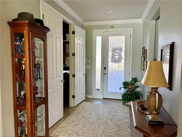 Doorway featuring light tile patterned flooring and ornamental molding