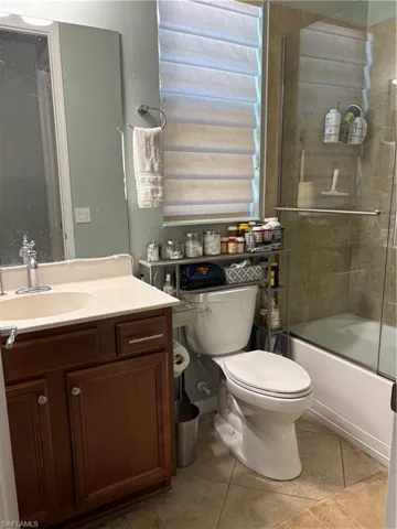 2nd Suite Full bath featuring tile patterned floors, vanity, toilet, and bath / shower combo with glass door