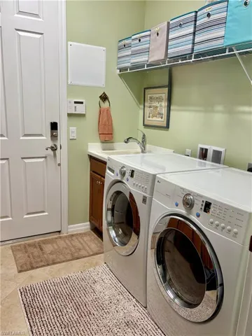 Washroom with cabinets, sink, washer and dryer, and light tile patterned flooring