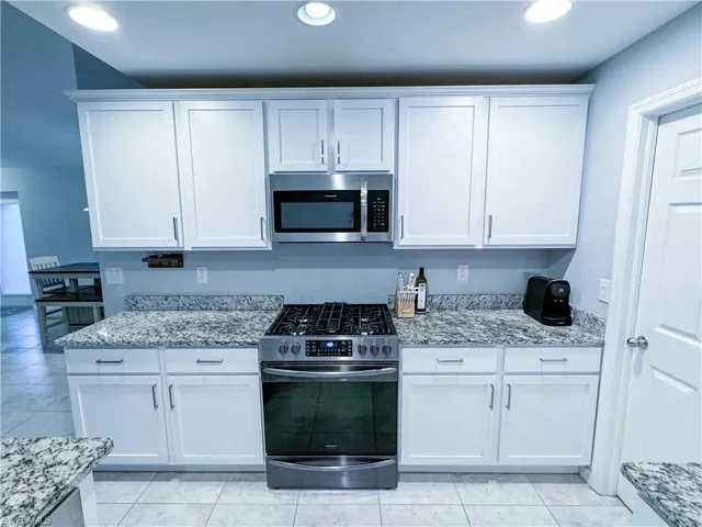 Kitchen featuring stainless steel appliances, white cabinetry, and light tile floors