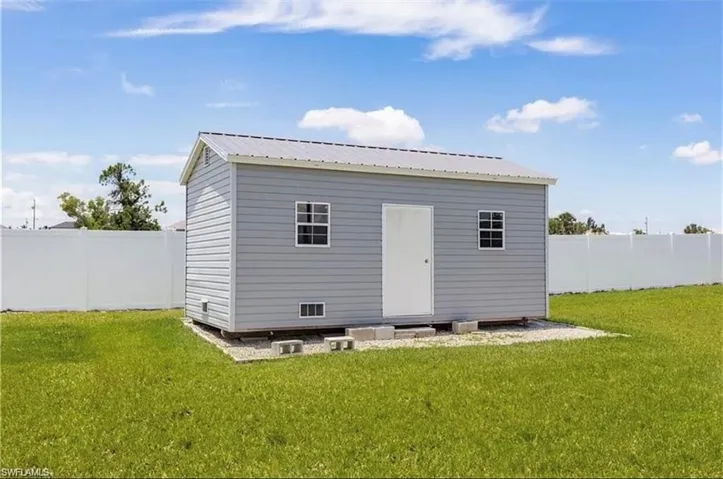 Back of house featuring a lawn and a storage shed