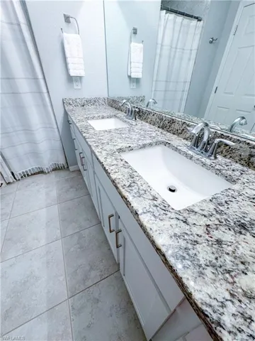 Bathroom with tile patterned flooring and dual bowl vanity