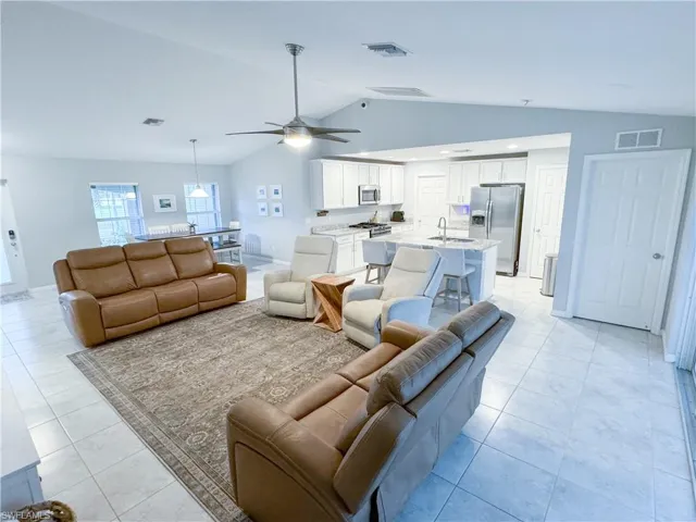 Tiled living room with vaulted ceiling, sink, and ceiling fan