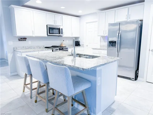 Kitchen featuring white cabinetry, light tile floors, and stainless steel appliances