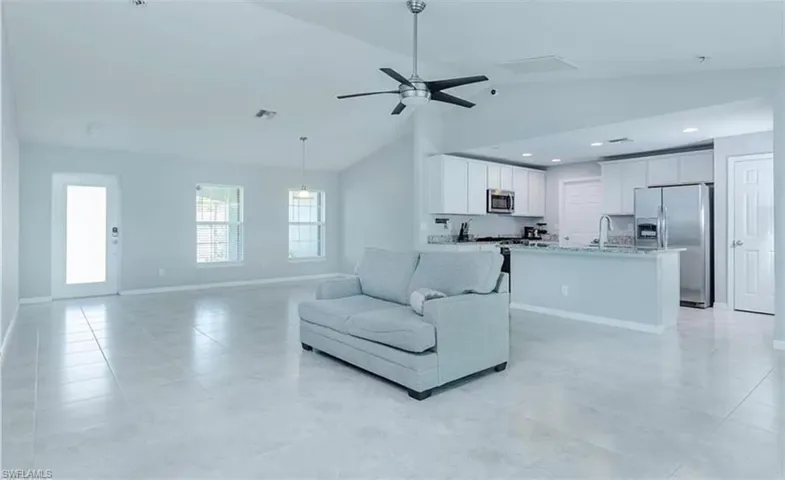 Living room with high vaulted ceiling, ceiling fan, sink, and light tile floors