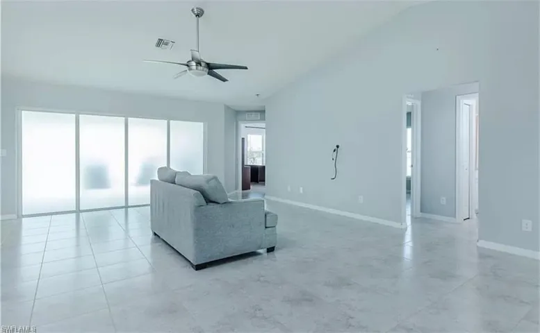 Tiled living room featuring ceiling fan and vaulted ceiling