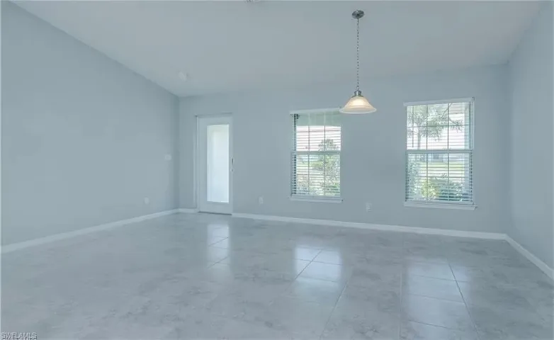 Tiled empty room featuring lofted ceiling