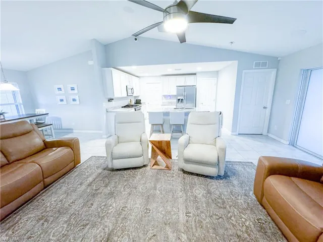 Living room with vaulted ceiling, ceiling fan, and light tile floors