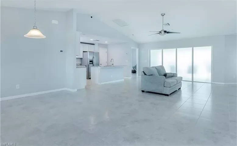 Unfurnished living room featuring high vaulted ceiling, ceiling fan, and light tile floors