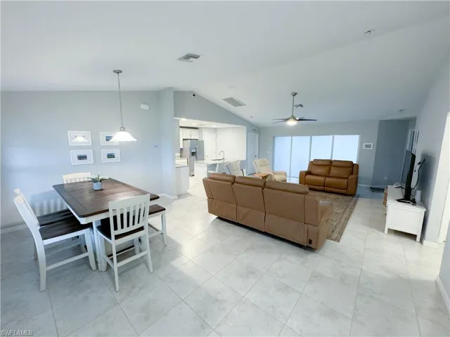 Living room with vaulted ceiling, sink, ceiling fan, and light tile floors