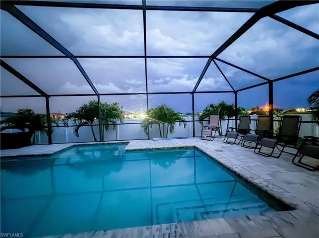 View of swimming pool featuring a patio and glass enclosure