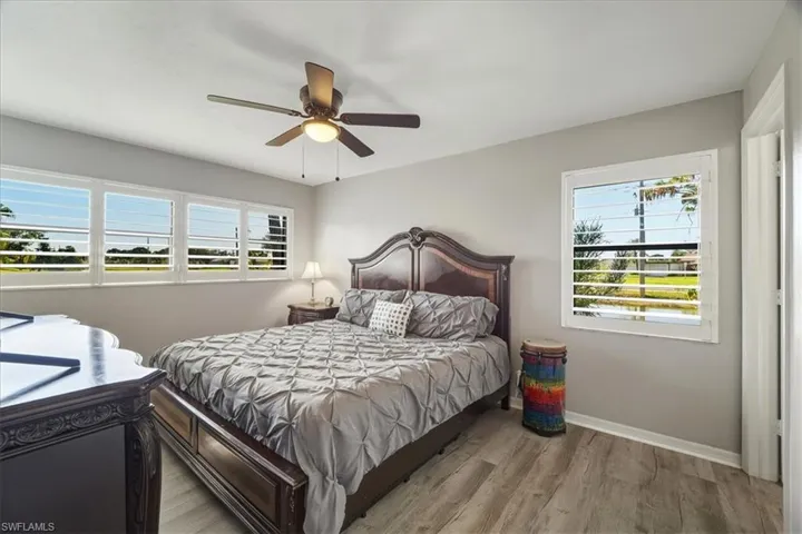 Bedroom with wood finished floors, ceiling fan, and multiple windows