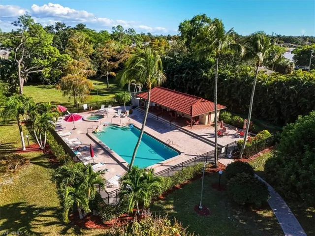 Community pool with a patio area, a community hot tub, and view of wooded area