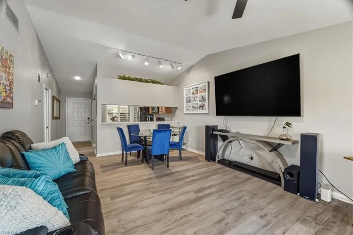Living room featuring lofted ceiling, light wood finished floors, a ceiling fan, and rail lighting