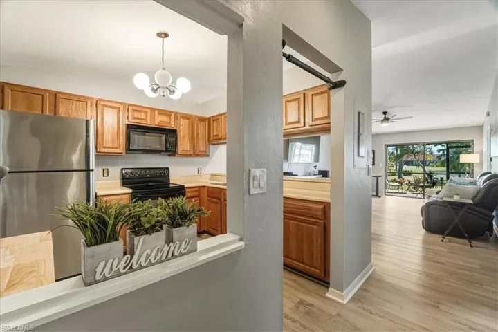 Kitchen with light countertops, black appliances, hanging light fixtures, light wood-type flooring, and a ceiling fan