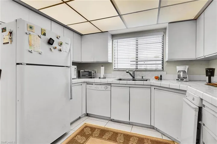 Kitchen featuring white appliances, tile counters, and light tile patterned flooring