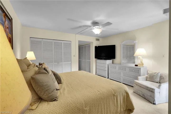 Bedroom featuring multiple closets, ceiling fan, and carpet