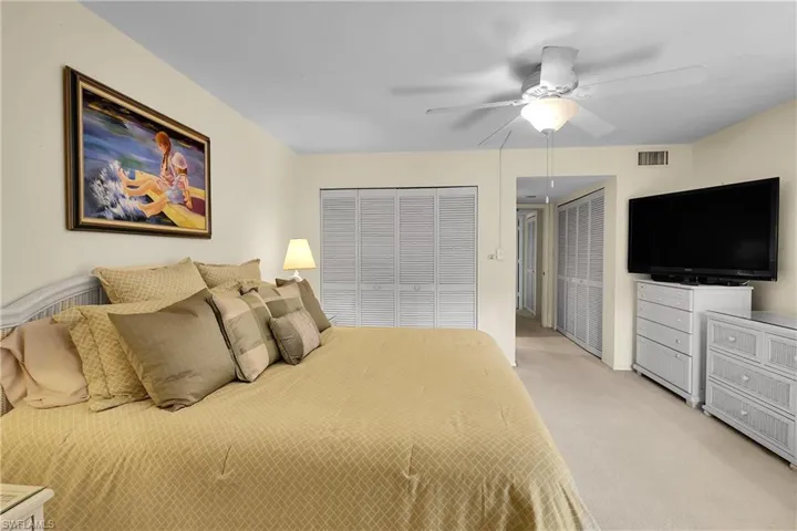Carpeted bedroom featuring multiple closets and ceiling fan
