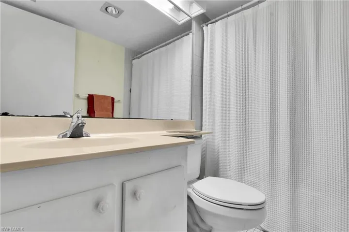 Bathroom with a shower with shower curtain, vanity, and a skylight