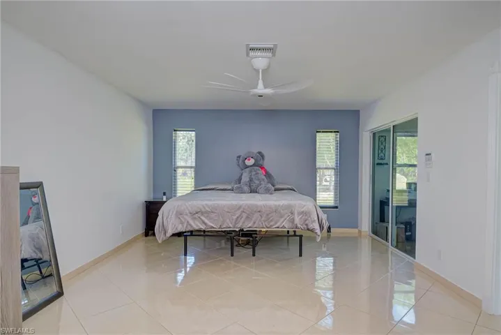 Bedroom featuring multiple windows, light tile patterned floors, and ceiling fan