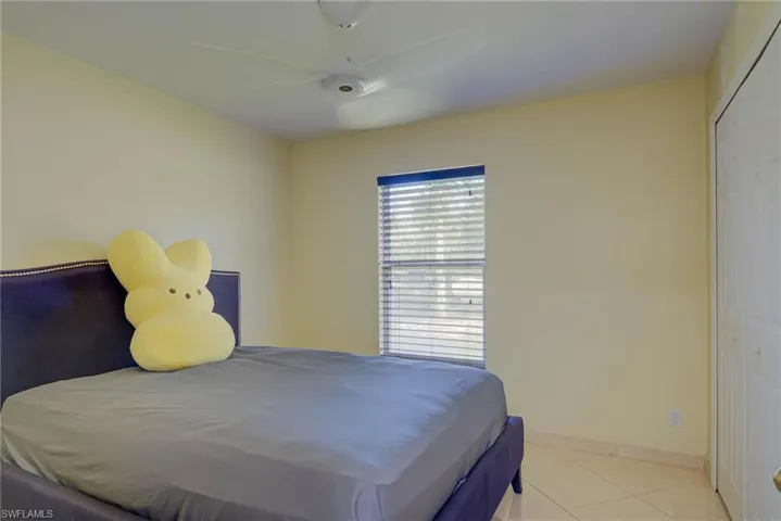 Bedroom featuring light tile patterned floors, ceiling fan, and a closet